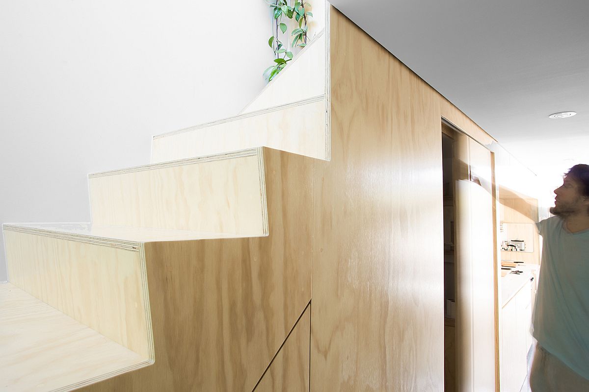 Custom storage space under the plywood staircase maximizes total square footage of the apartment