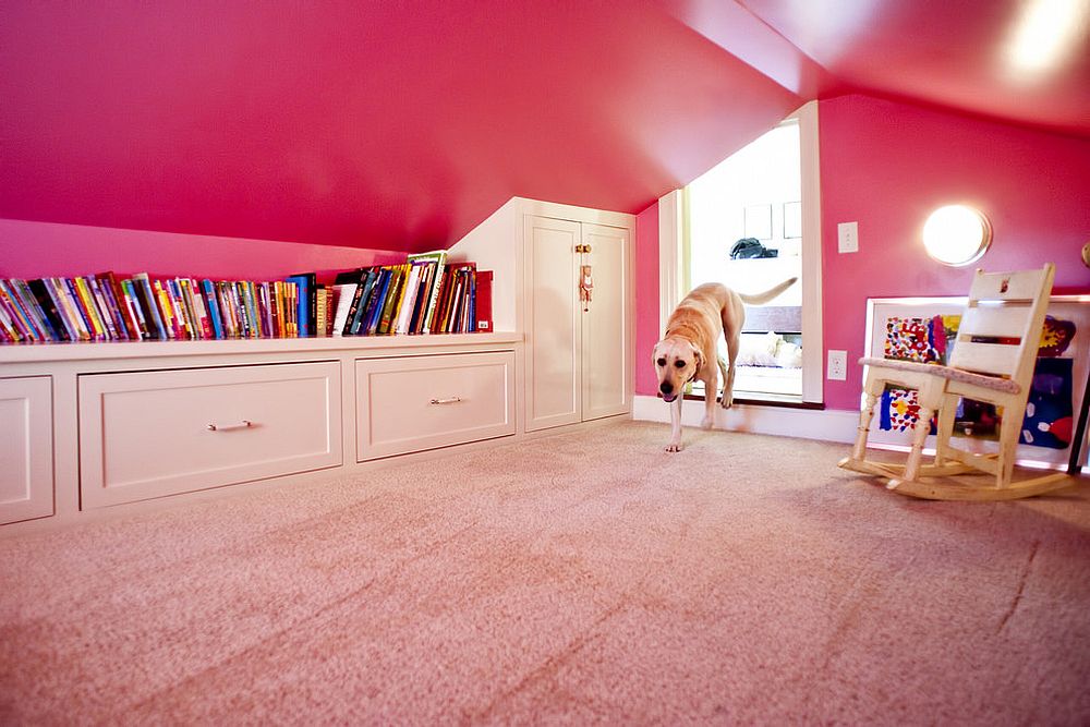 Girls' attic playroom with plenty of built-in shelving and walls draped in pink