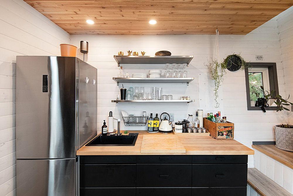 Kitchen inside the small island home with dark island, stainless steel applainces and wooden countertops