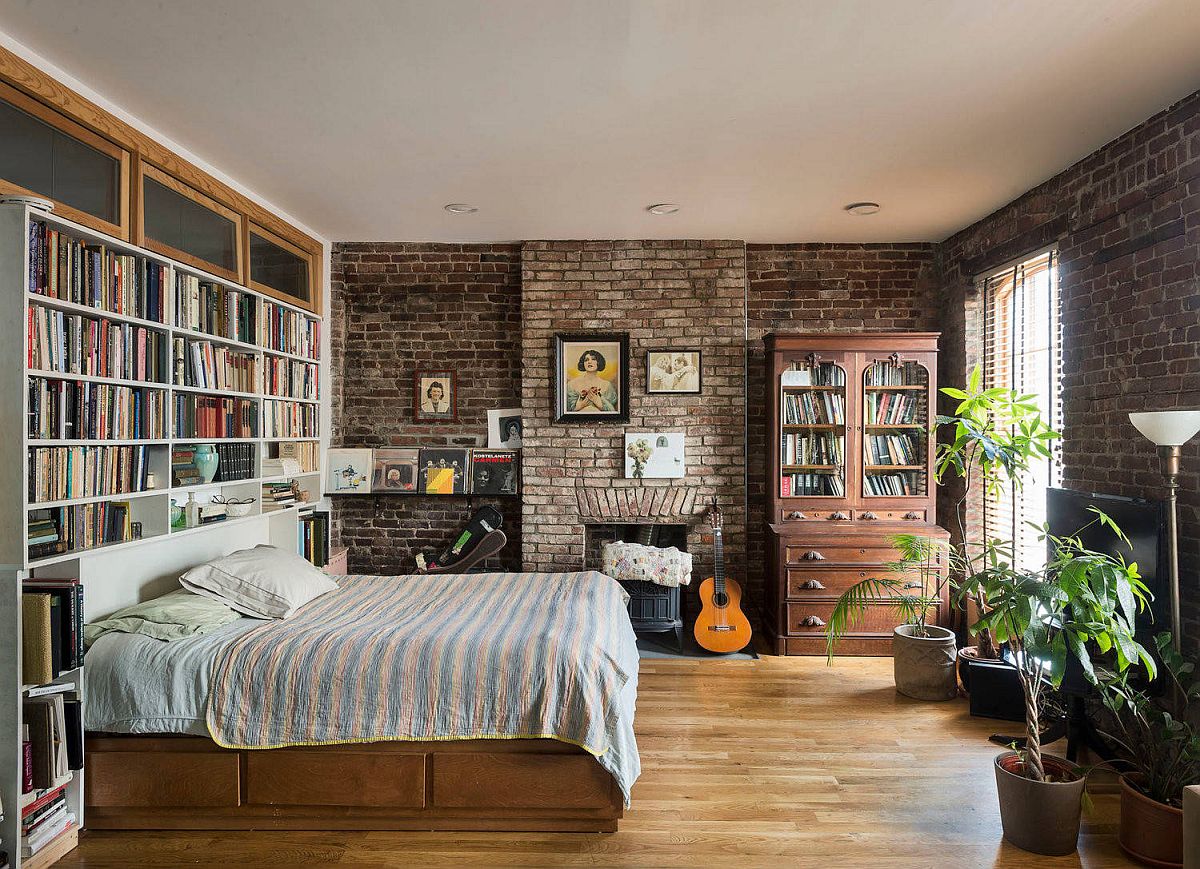 Large bookshelf for the modern industrial bedroom with brick walls and a comfy bed