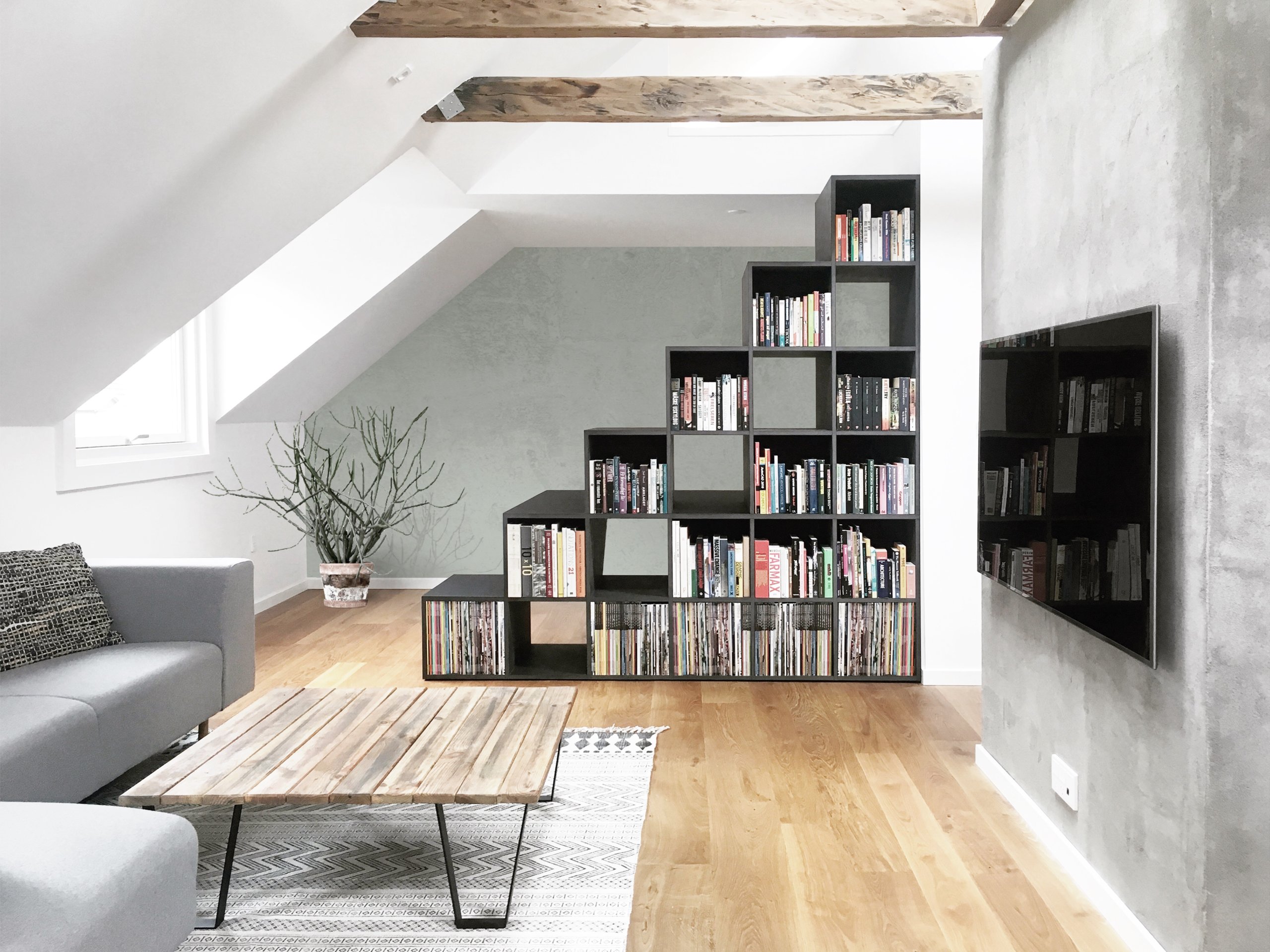 Living area in neutral hues with light gray couch and a lovely bookshelf