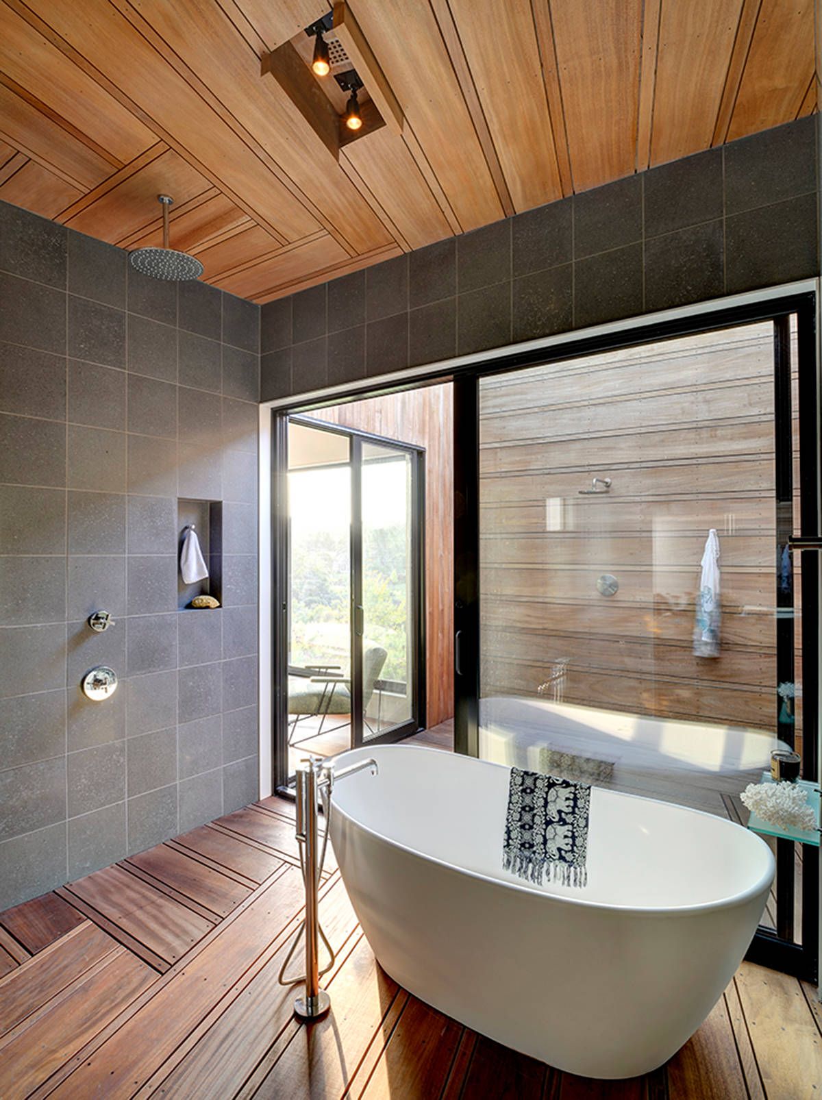 Modern bathroom of New York home in gray and wood with freestanding bathtub and rainfall shower