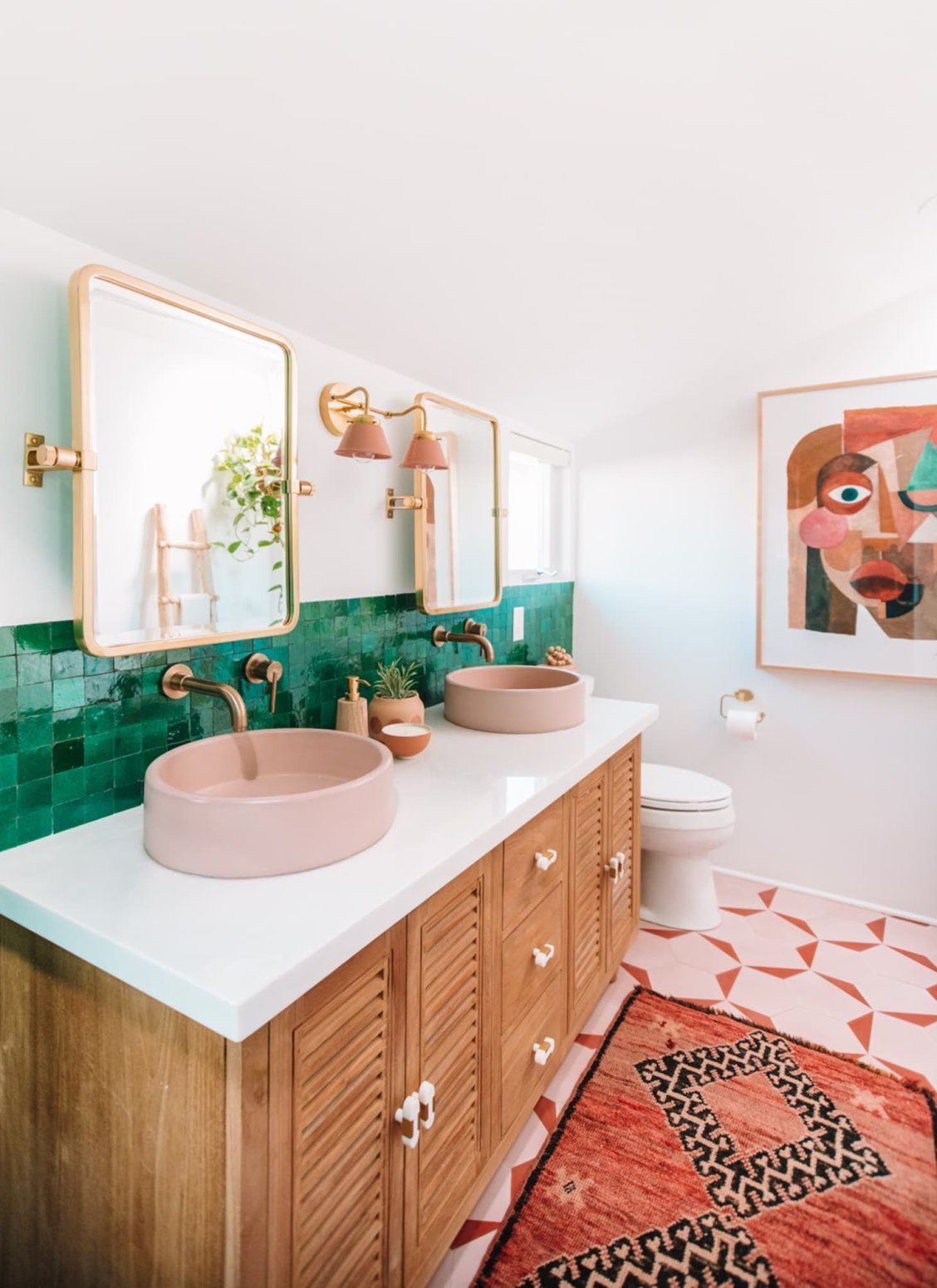 Pair of gold-trimmed mirrors over a pair of pink sinks