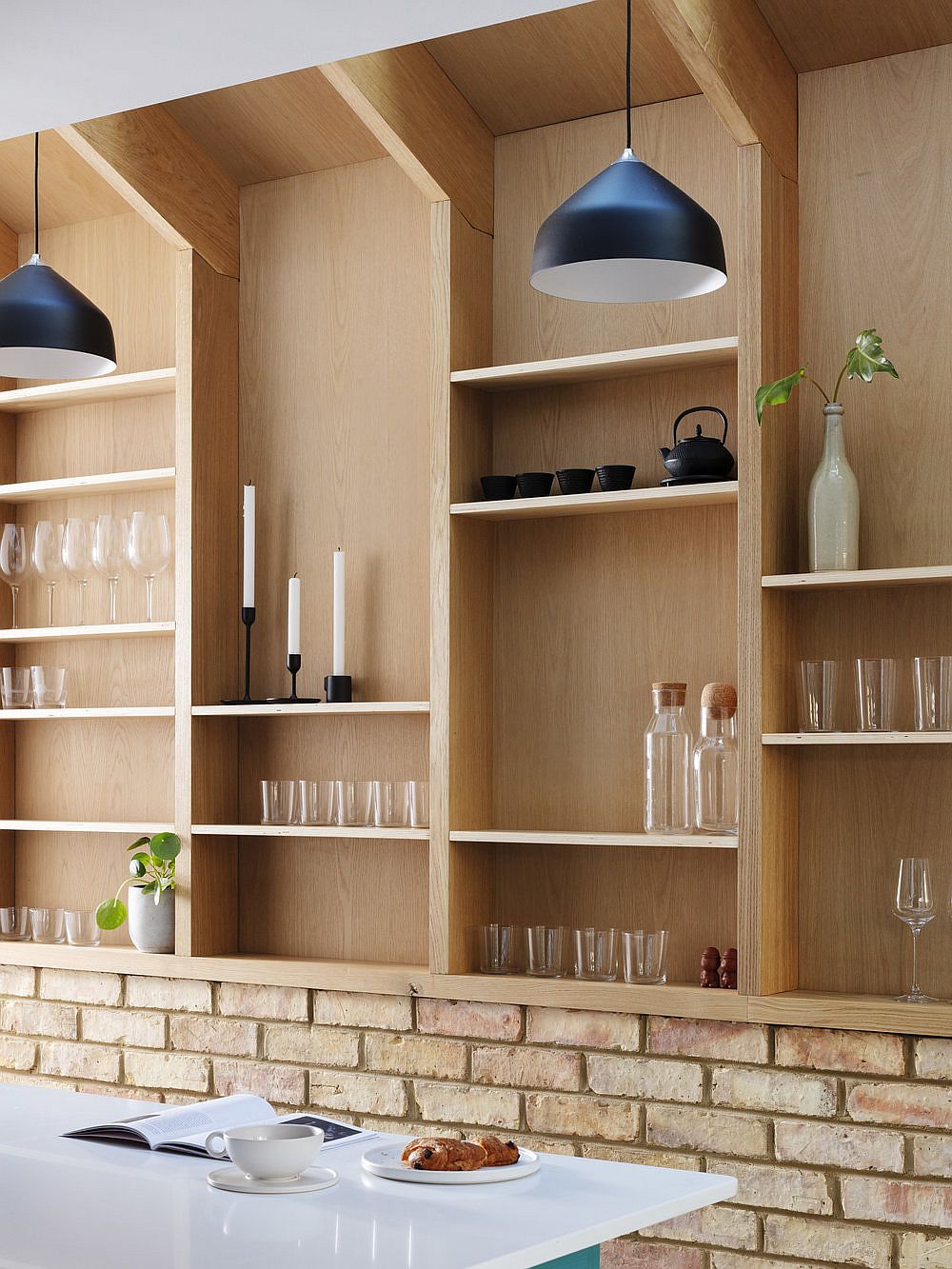 Pendants in black add visual contrast to the interior draped in wood and brick