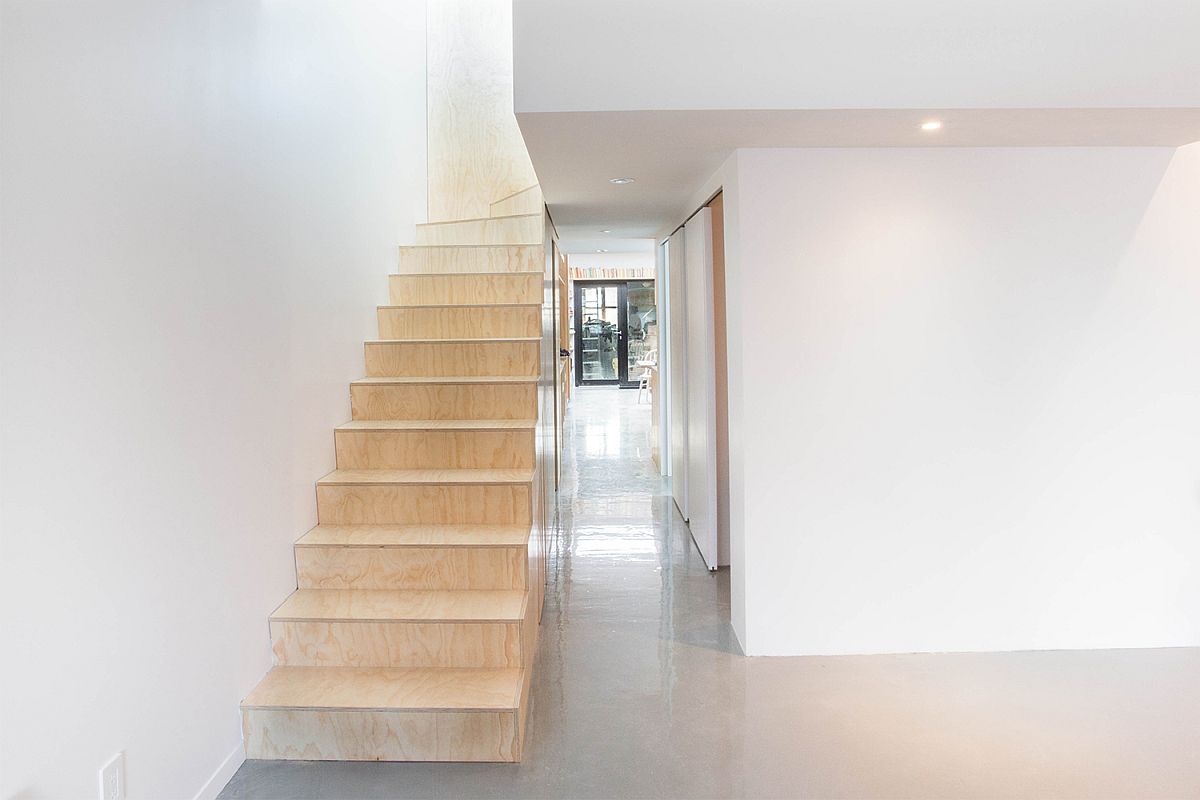 Plywood furniture and staircase inside the white revamped Artist's apartment in France