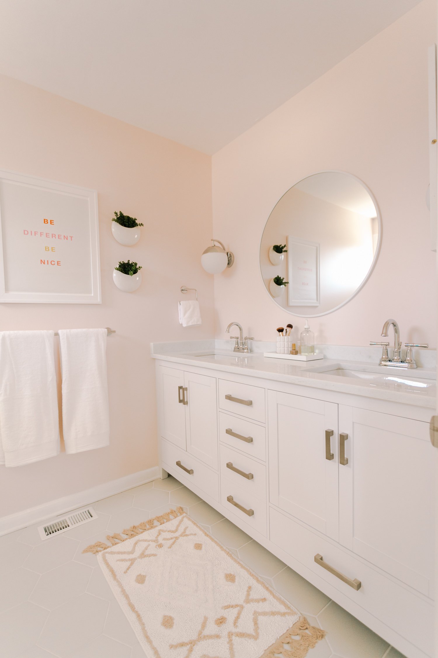 Round white mirror in a blush bathroom