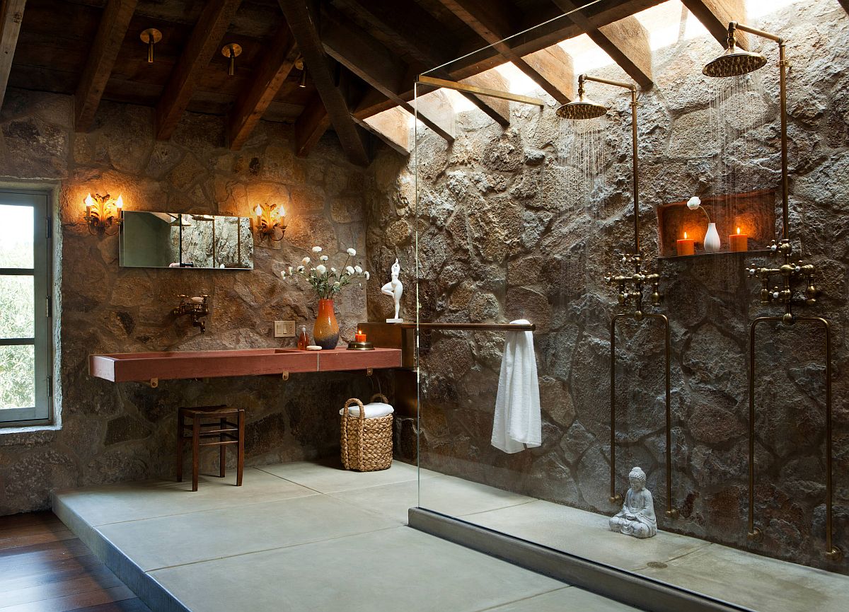 Serene modern rustic bathroom with stone walls and a glass shower area with rainfall shower