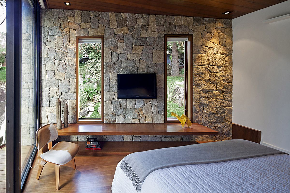 Simple floating wooden desk se against stone walls inside the bedroom