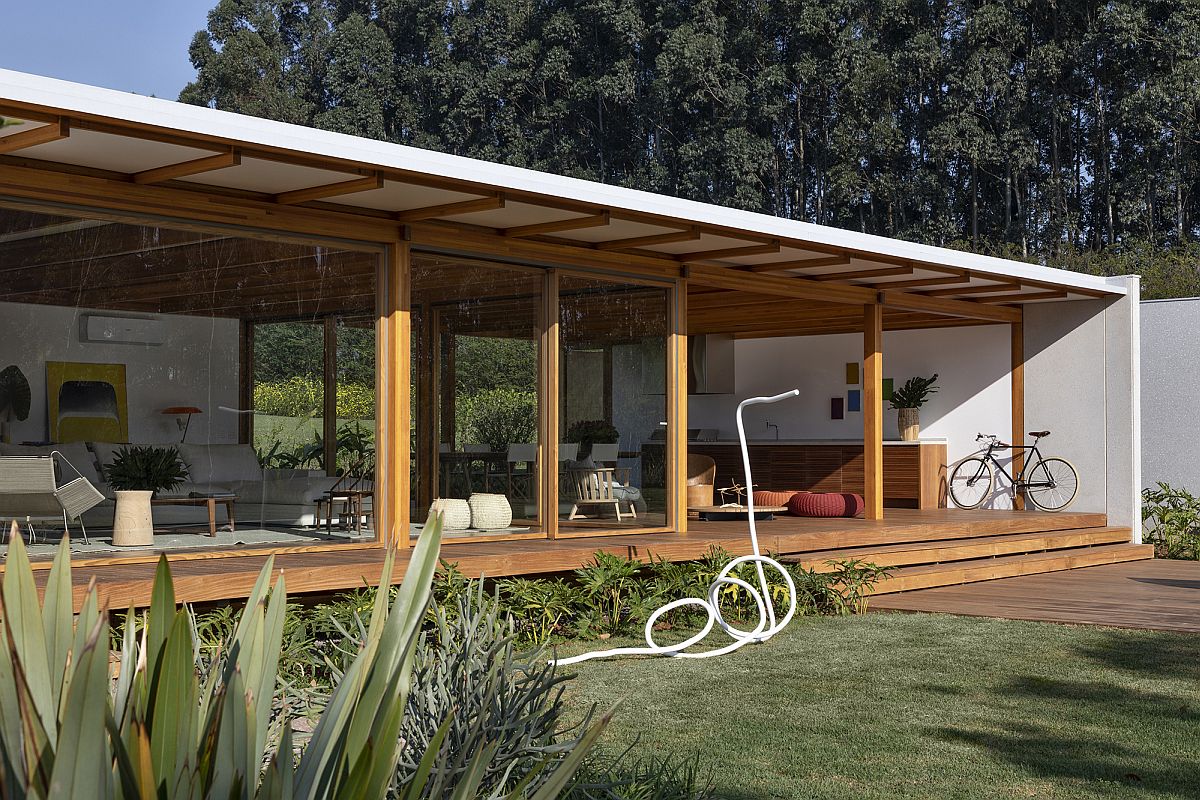 Sliding glass walls with wooden frame connect the spacious interior with the landscape outside