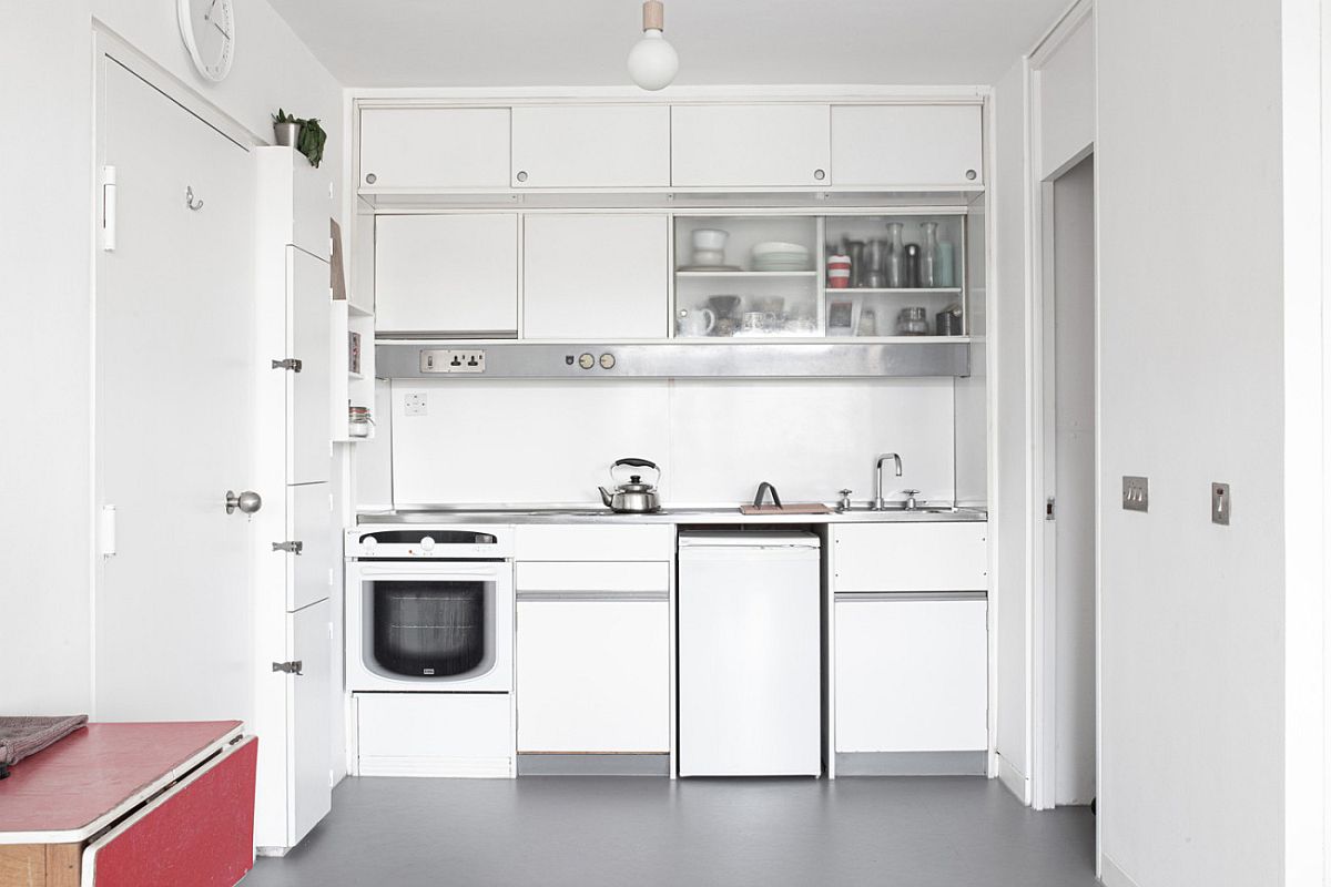 Small single-wall kitchen in white inside the studio apartment in London