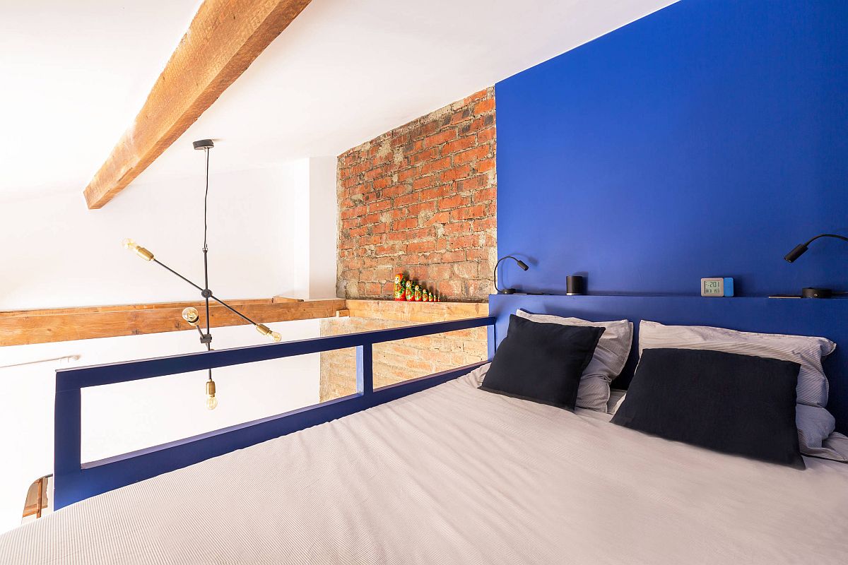 Tiny industrial bedroom with a blue accent wall and super-stylish design