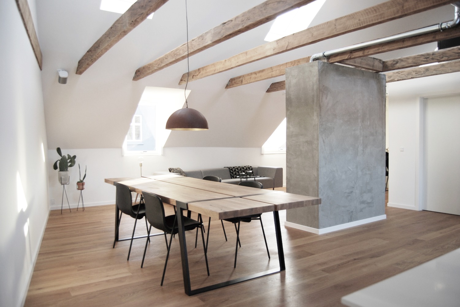 Wooden ceiling beams and concrete wall section in the dining area of the apartment