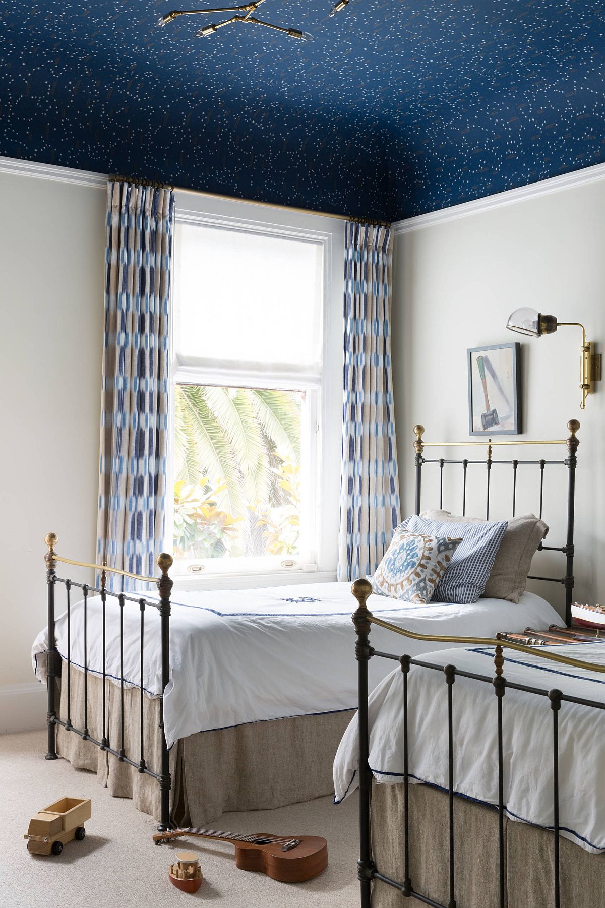 Dashing dark blue wallpaper on the ceiling adds bright color to this kids' bedroom