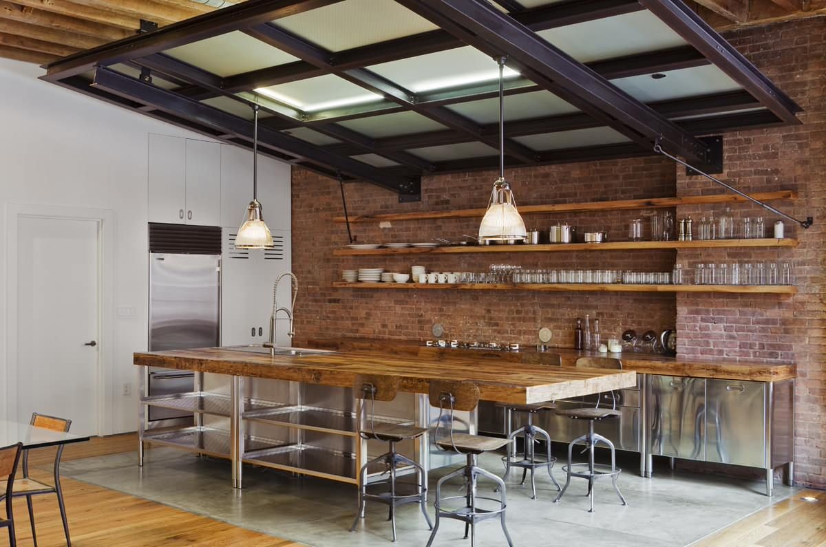 Industrial-farmhouse style kitchen with exposed brick wall backdrop and sleek wooden floating shelves