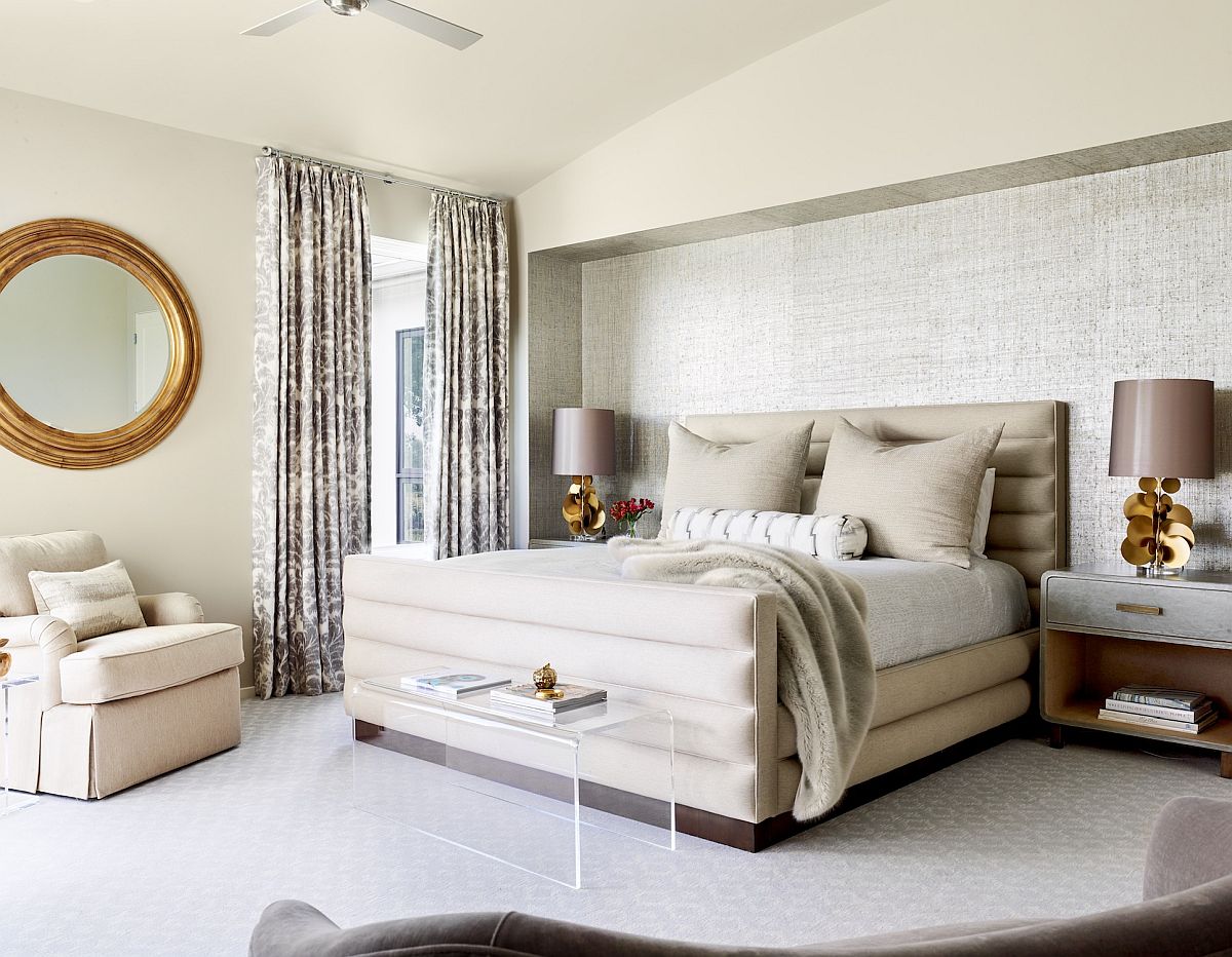 Master bedroom in white where the bedside table lamps bring symmetry to the large space