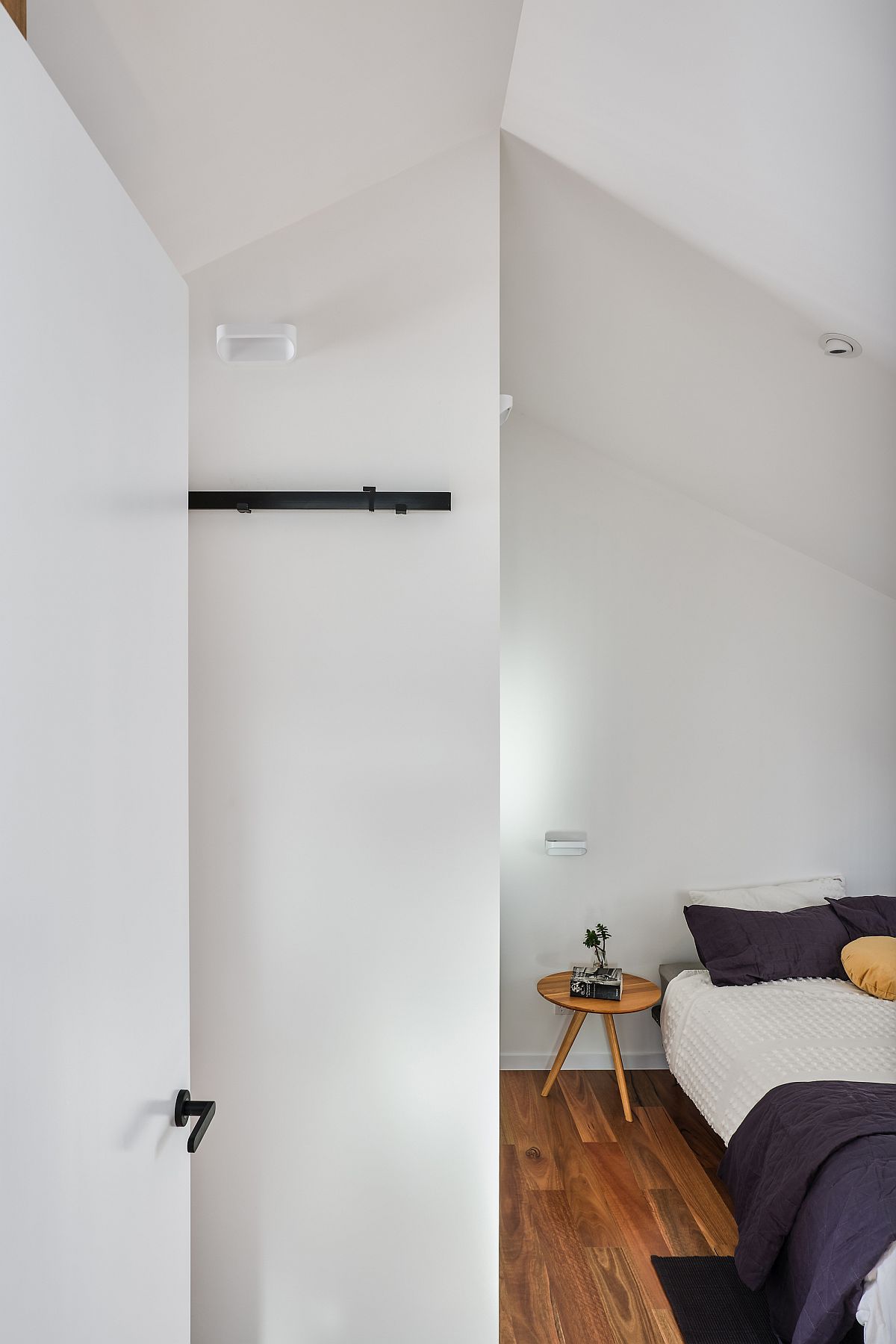 Attic level bedroom of the house with white walls and a wooden floor