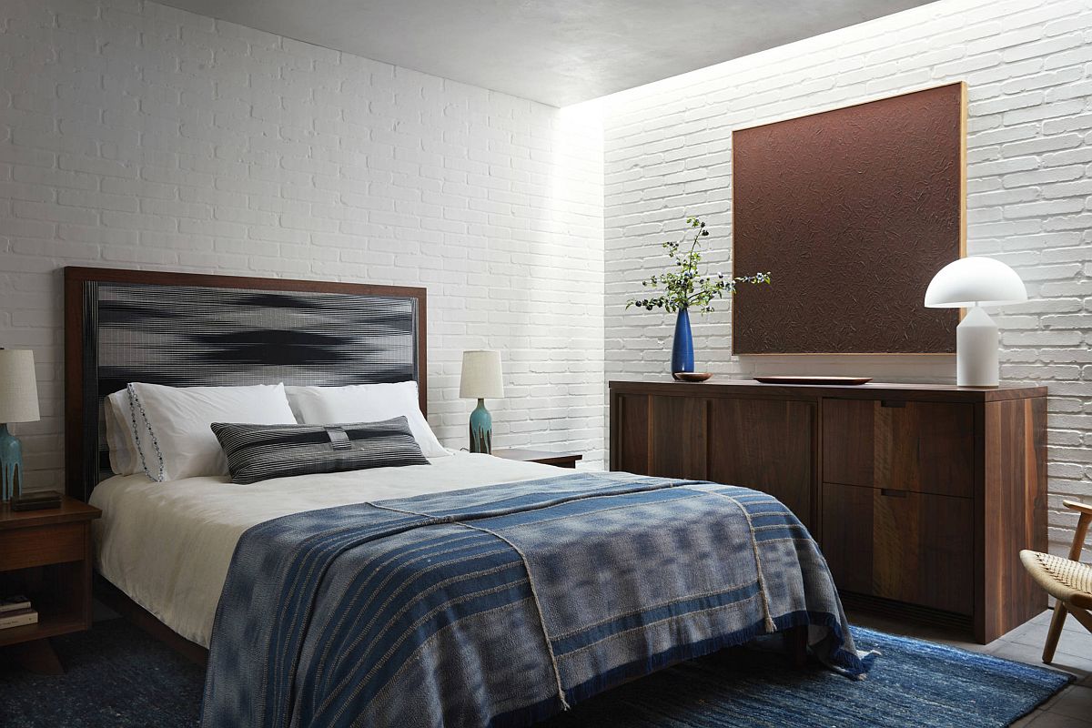 Blue accents, wooden decor and whitewashed brick walls create a cozy, relaxing bedroom