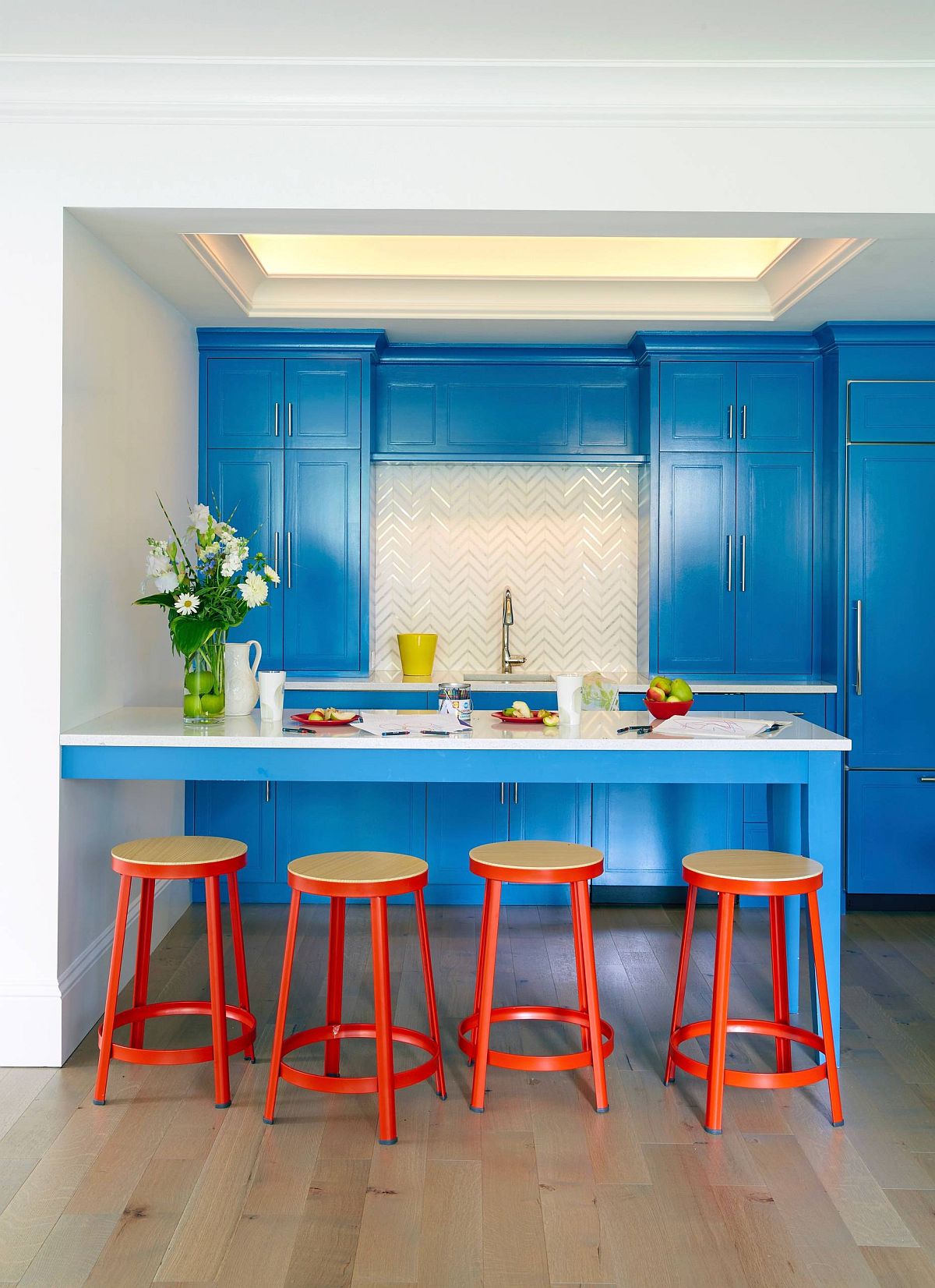 Eclectic blend of blue and orange inside the vivacious NYC kitchen with ample storage space