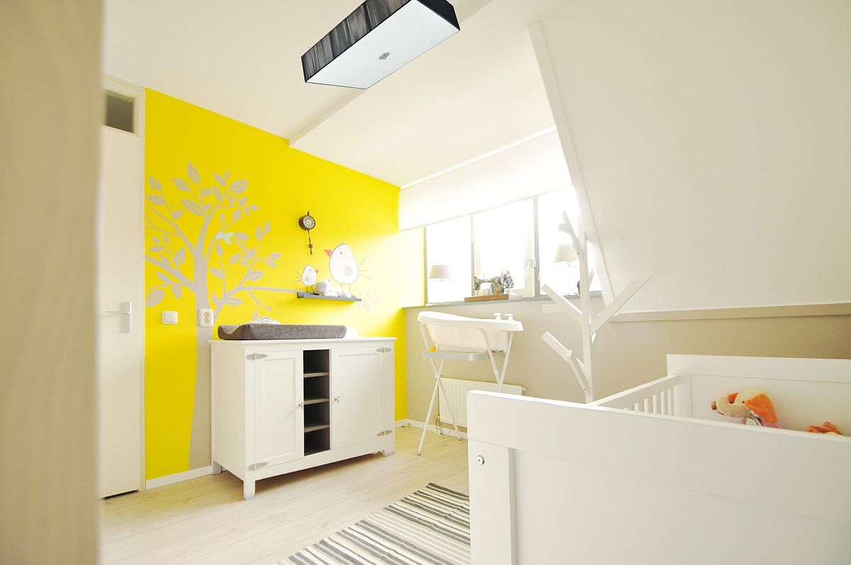 Exquisite white gender-neutral nursery of Amsterdam home with a brilliant yellow accent wall