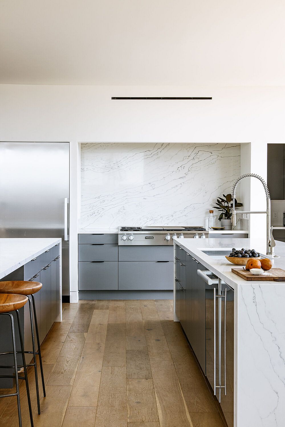 Light bluish-gray cabinets in the kitchen offer contrast to the wood and white interior