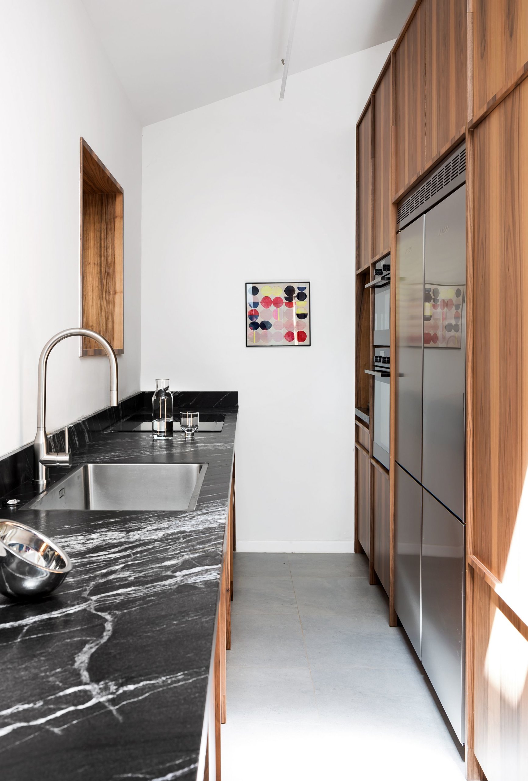 Long countertop in granite on the left and wooden cabinets on the right inside the narrow kitchen