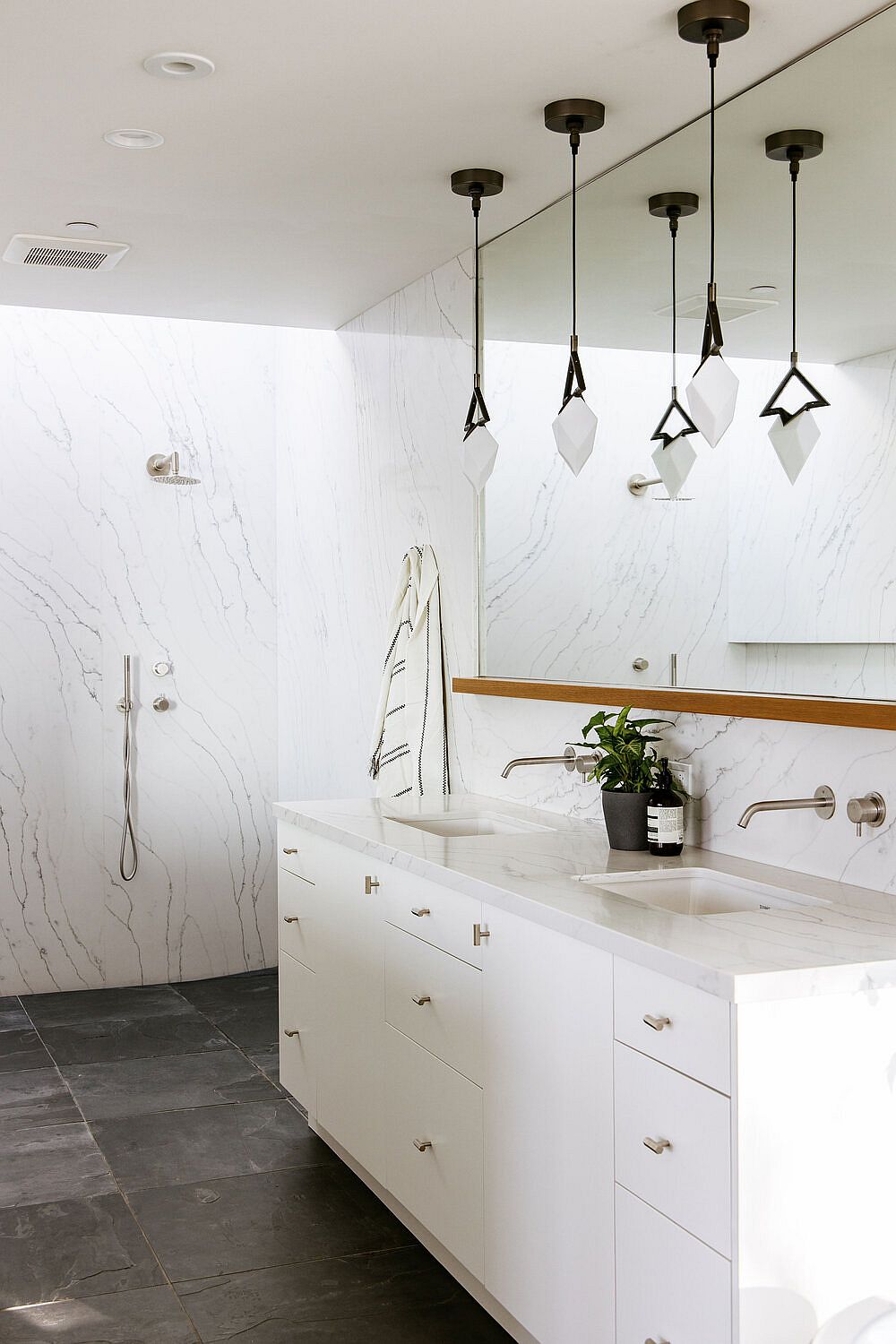 Marble finishes and countertops in the bathroom are coupled with dark stone flooring