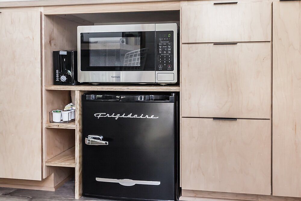 Microwave and small refrigerator inside the tiny kitchen that become a part of the cabinets