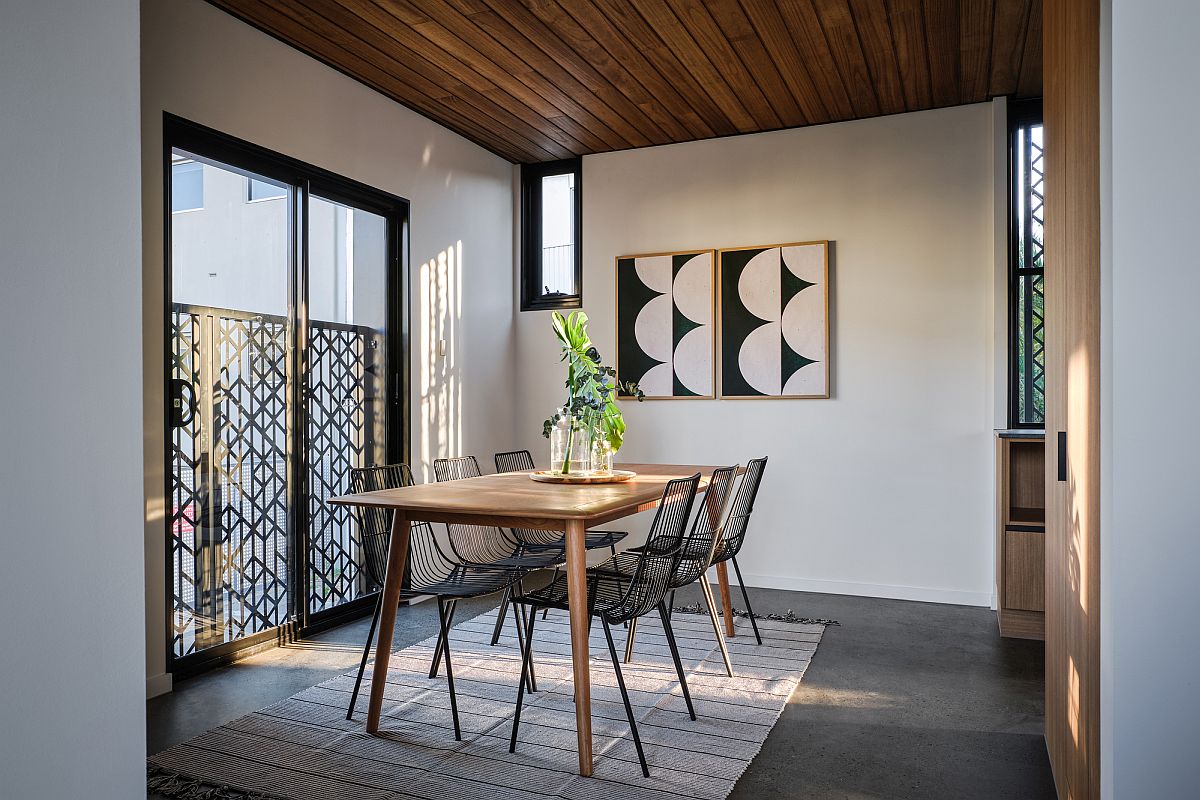 Modern dining room with a flood of sunlight, wooden ceiling and a modern minimal table and chairs