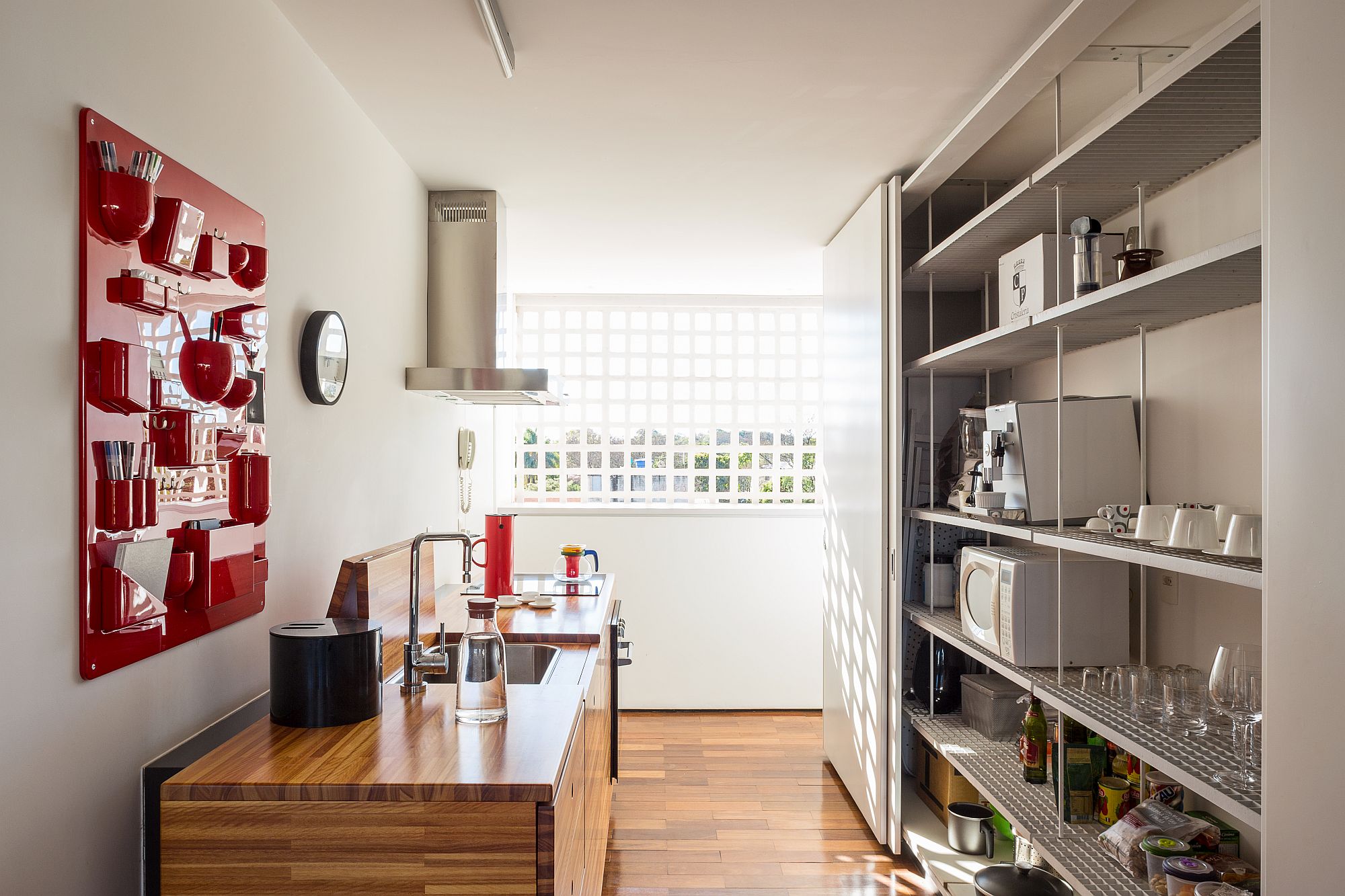 Modern kitchen with red accent storage system and stainless steel shelves