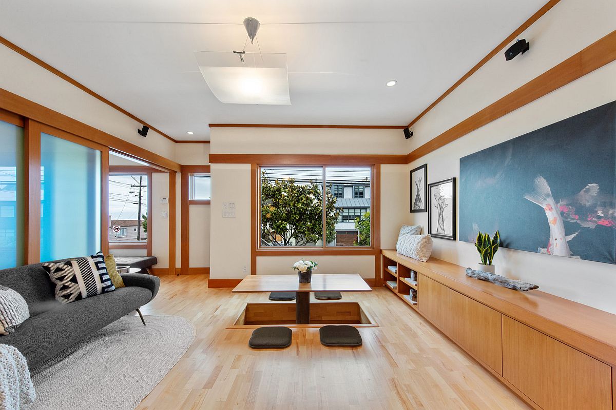 Modest Japanese style living room in wood and white with a low-slung couch in dark gray