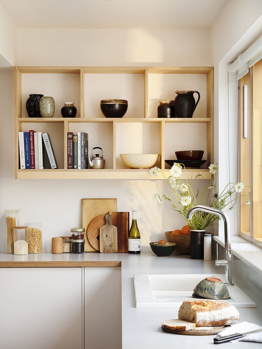 Open shelves in the corner create an eye-catching display in the modern white kitchen