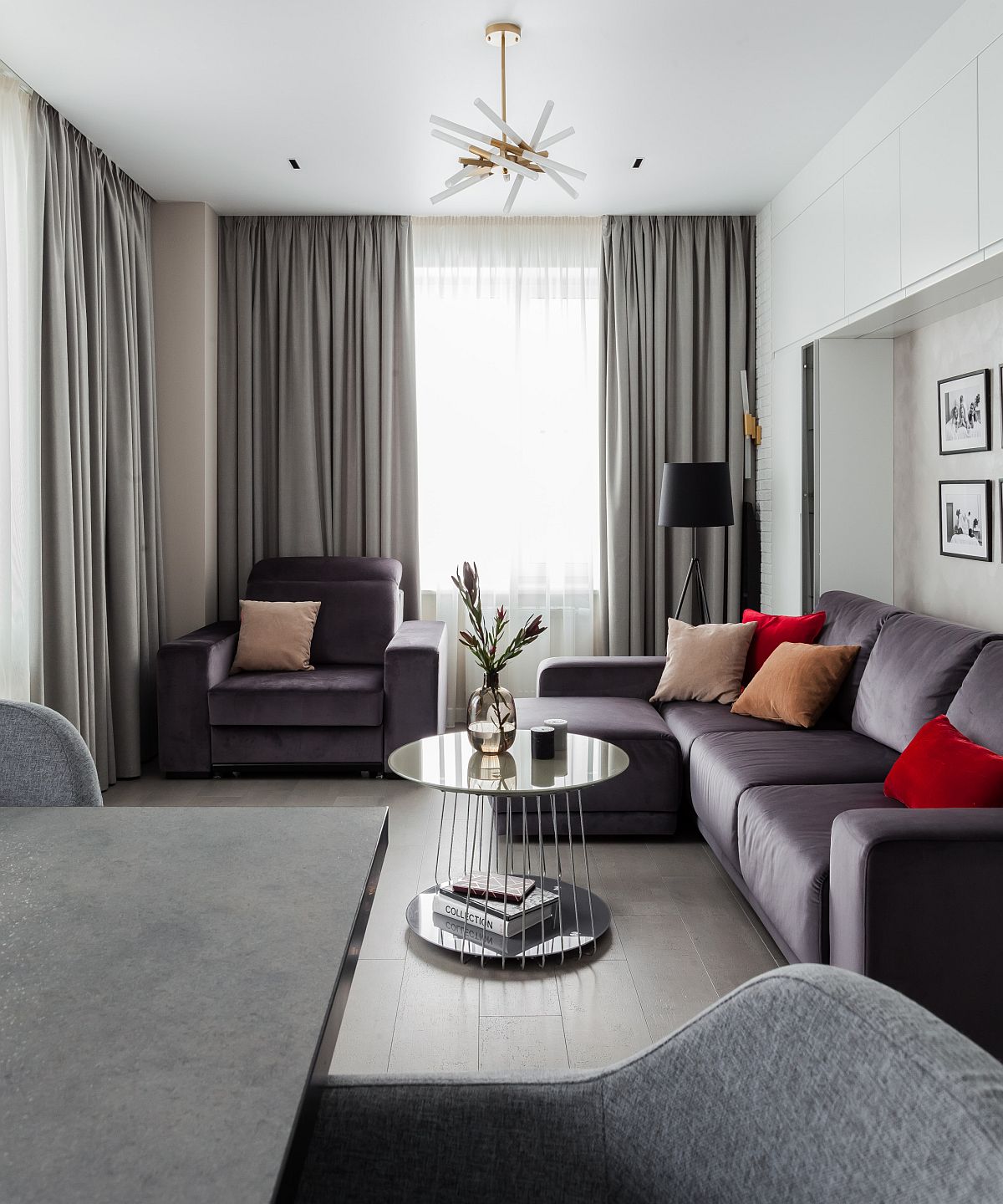 Sectional in gray adds to the color scheme of the tiny living room with red accents