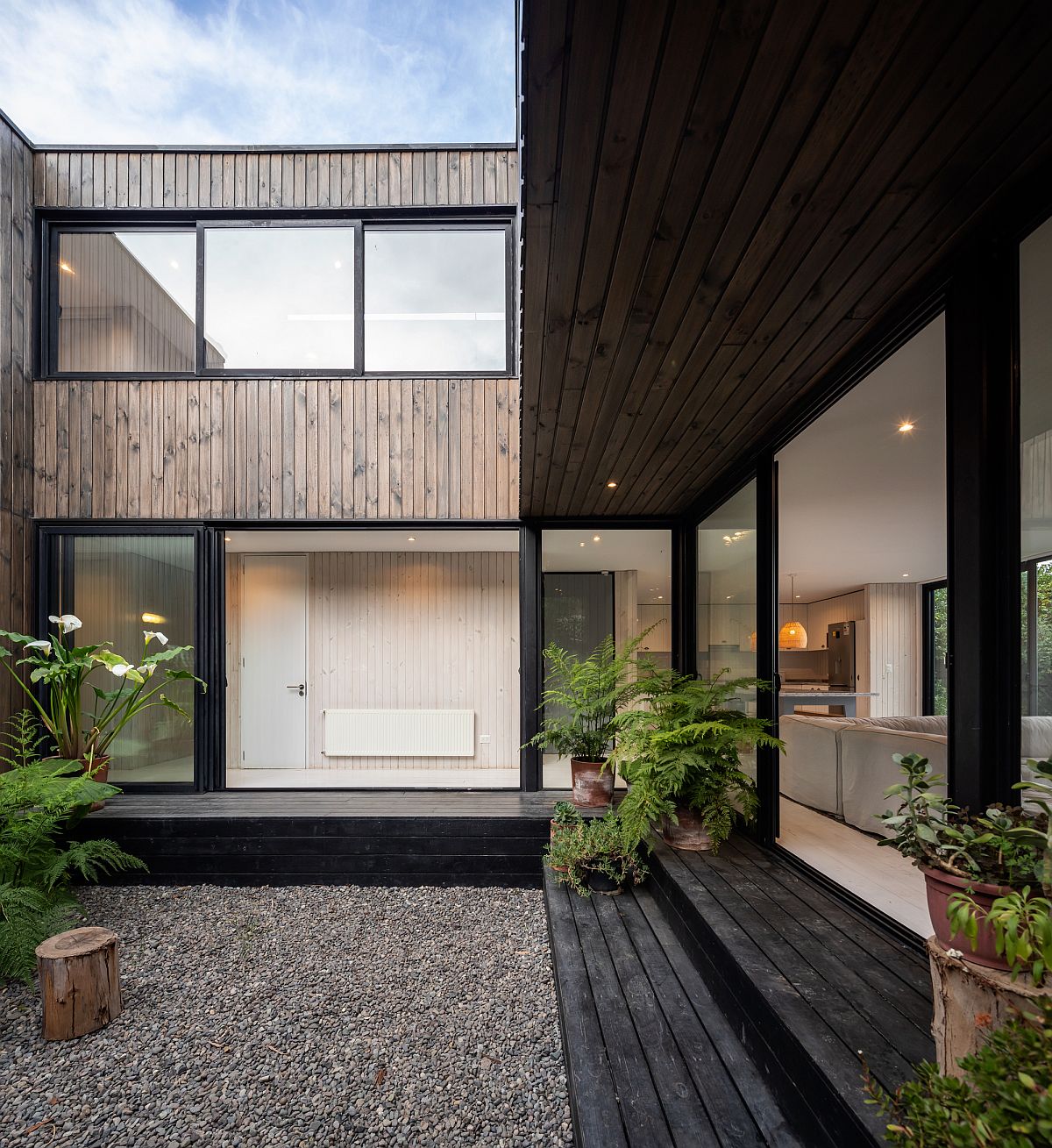 Sliding glass doors with steel frame and wood shape the exterior of the house