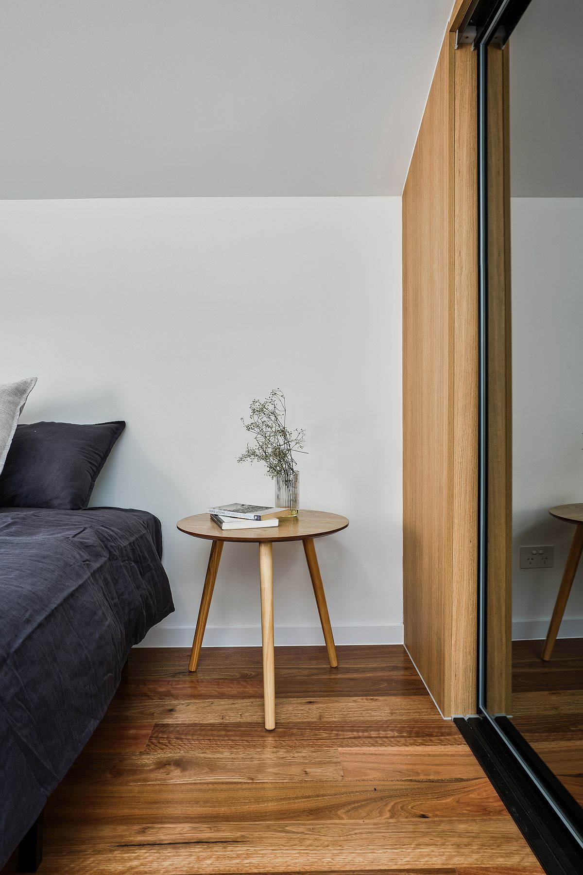 Space-conscious and stylish modern bedroom in white with warm wooden floor and mirrored wardrobe