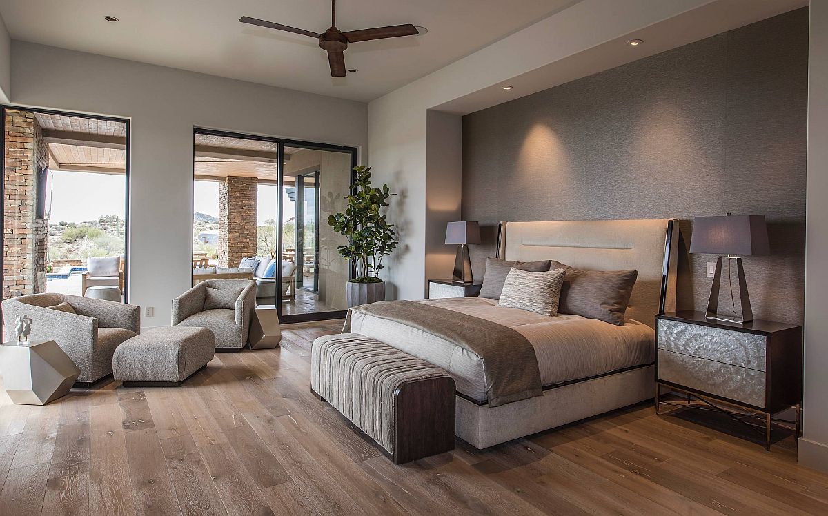 Spacious bedroom of home in Phoenix with a textured gray accent wall, wooden floor and striking bedside lamps