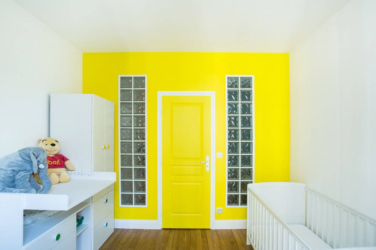 Yellow accent wall and door create a stunning visual focal point in this contemporary Paris nursery