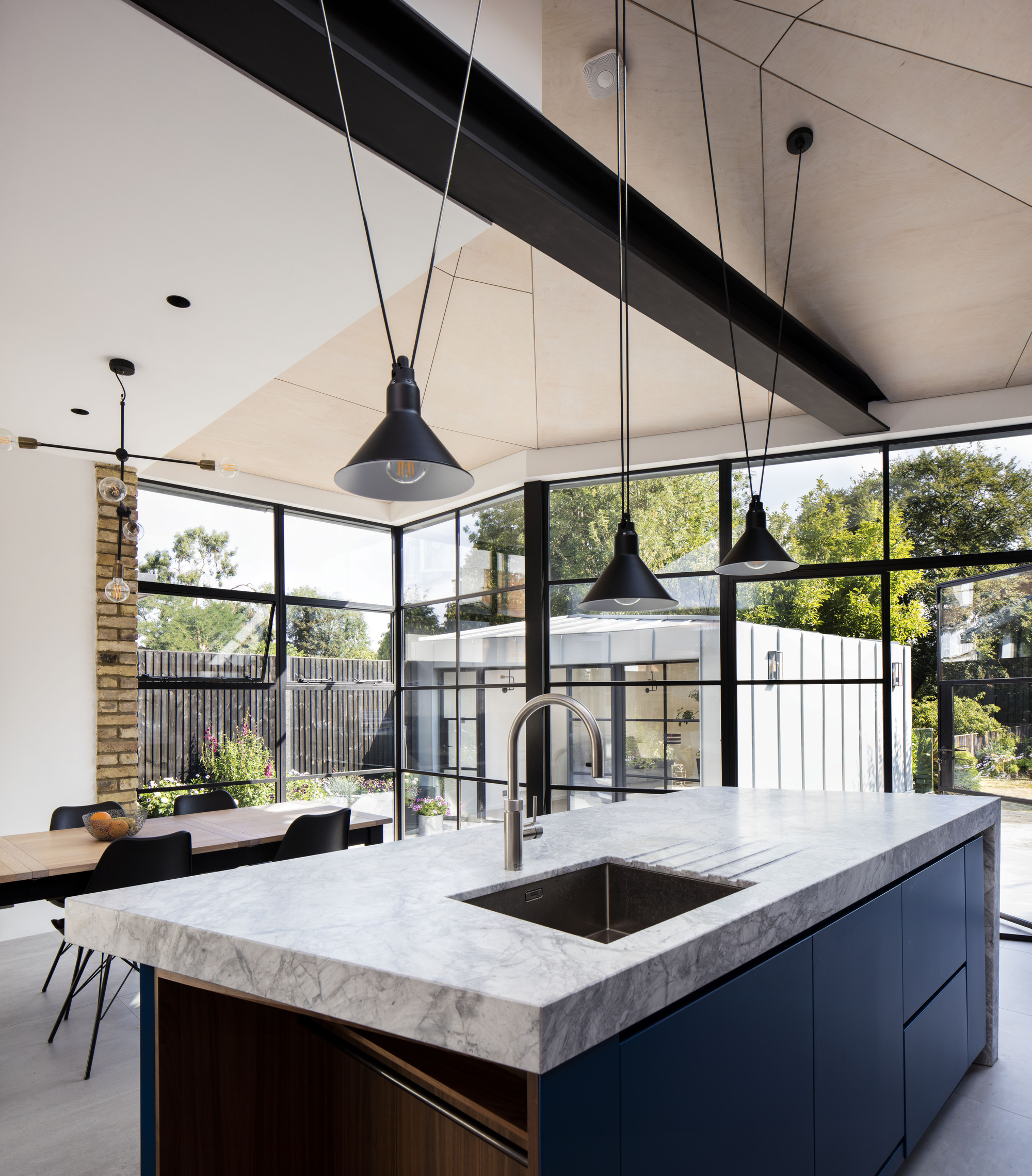 Angular plywood roof, custom kitchen island and dining space of the renovated London home