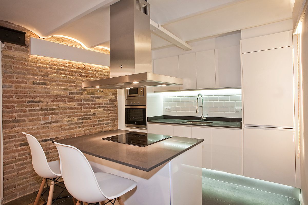 Beautiful modern industrial kitchen of Barcelona home with an exposed brick wall and walls in white