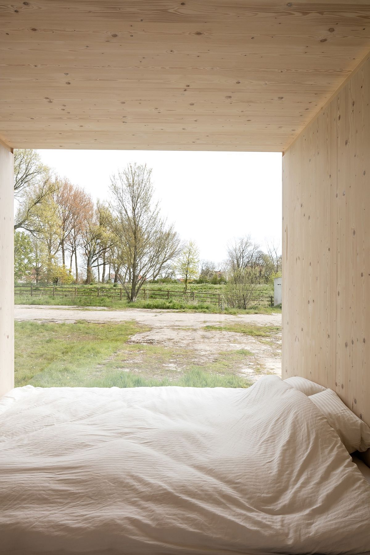 Bedroom of the cabin in light wood tones offers seamless connectivity with the outdoors