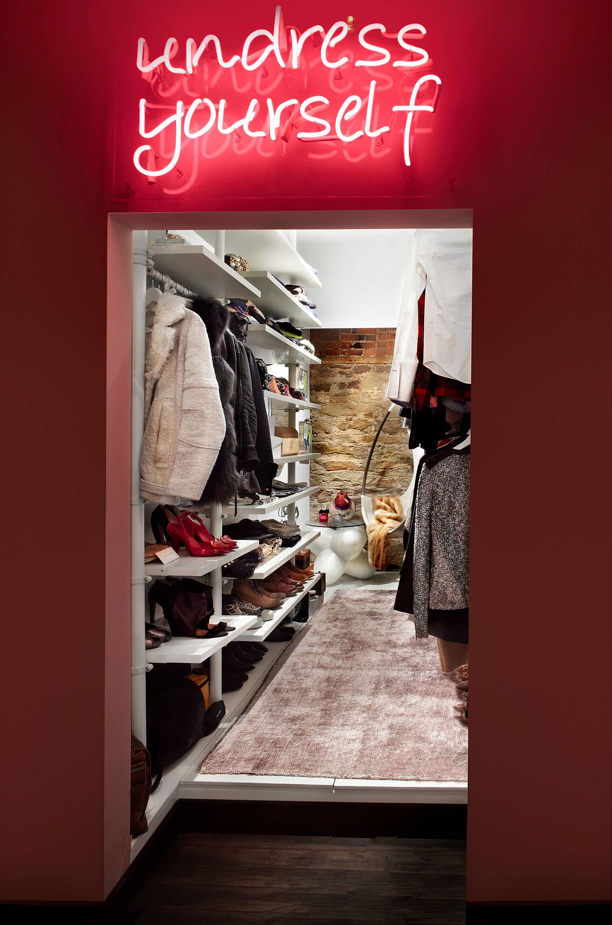 Chic eclectic walk-in closet with neon lighting and an exposed brick wall inside