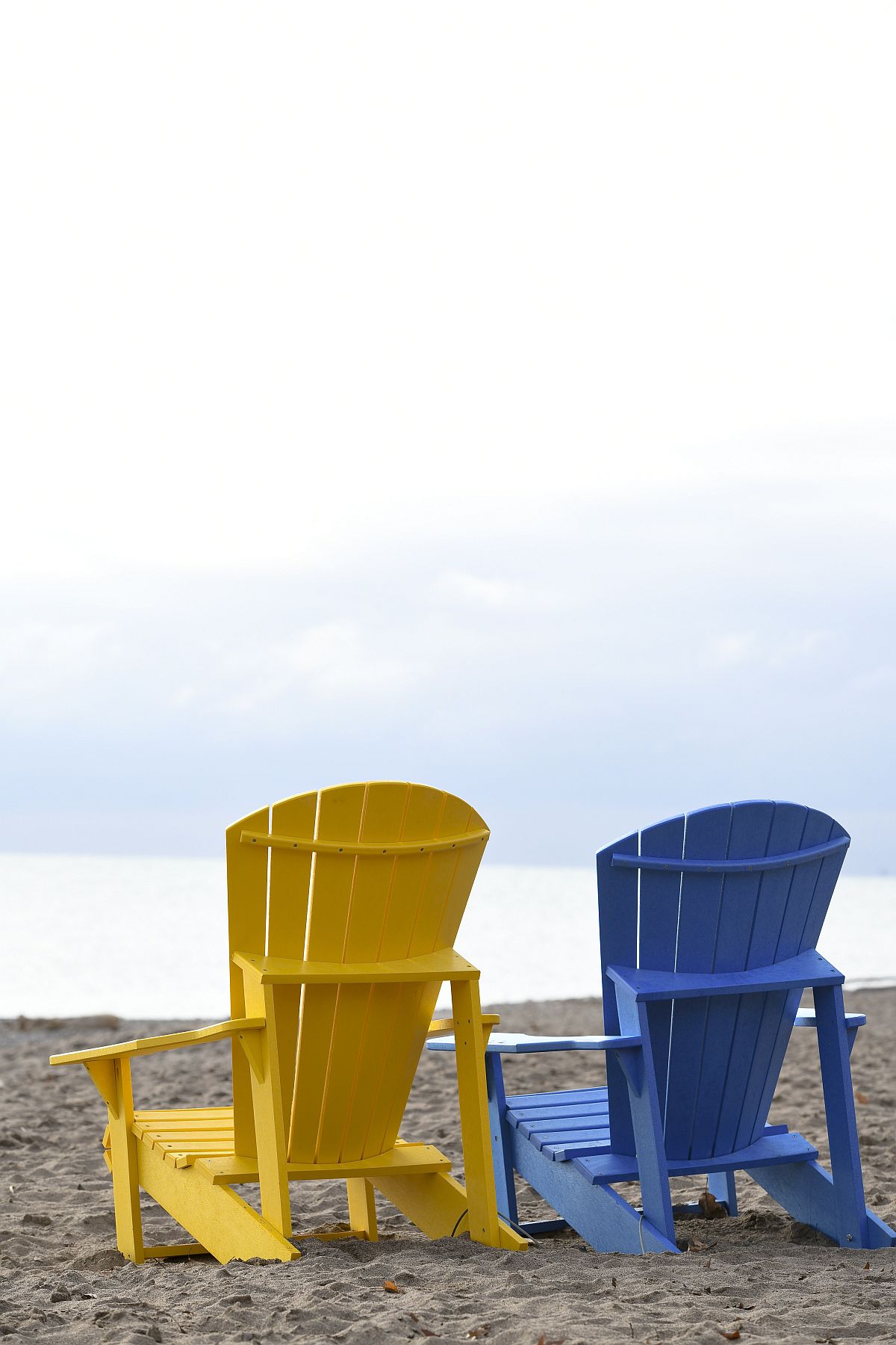 Colorful wooden chairs on the beach offer lovely views of the waves and beyond