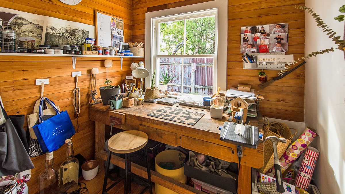 Cozy and beautiful wooden walls create a lovely ambiance in this tiny crafts room that is filled with supplies