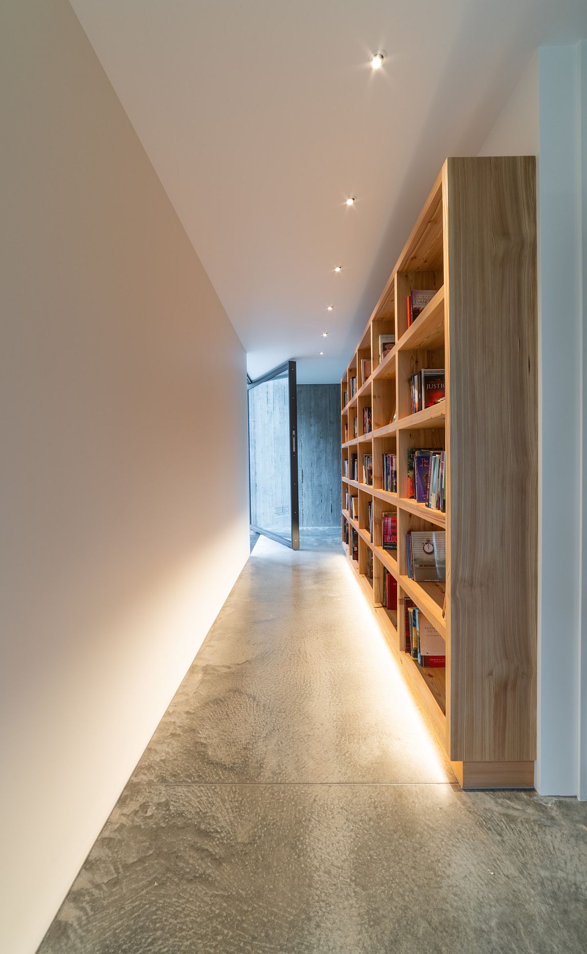 Custom wooden bookshelf in the hallway adds something different to the modern home