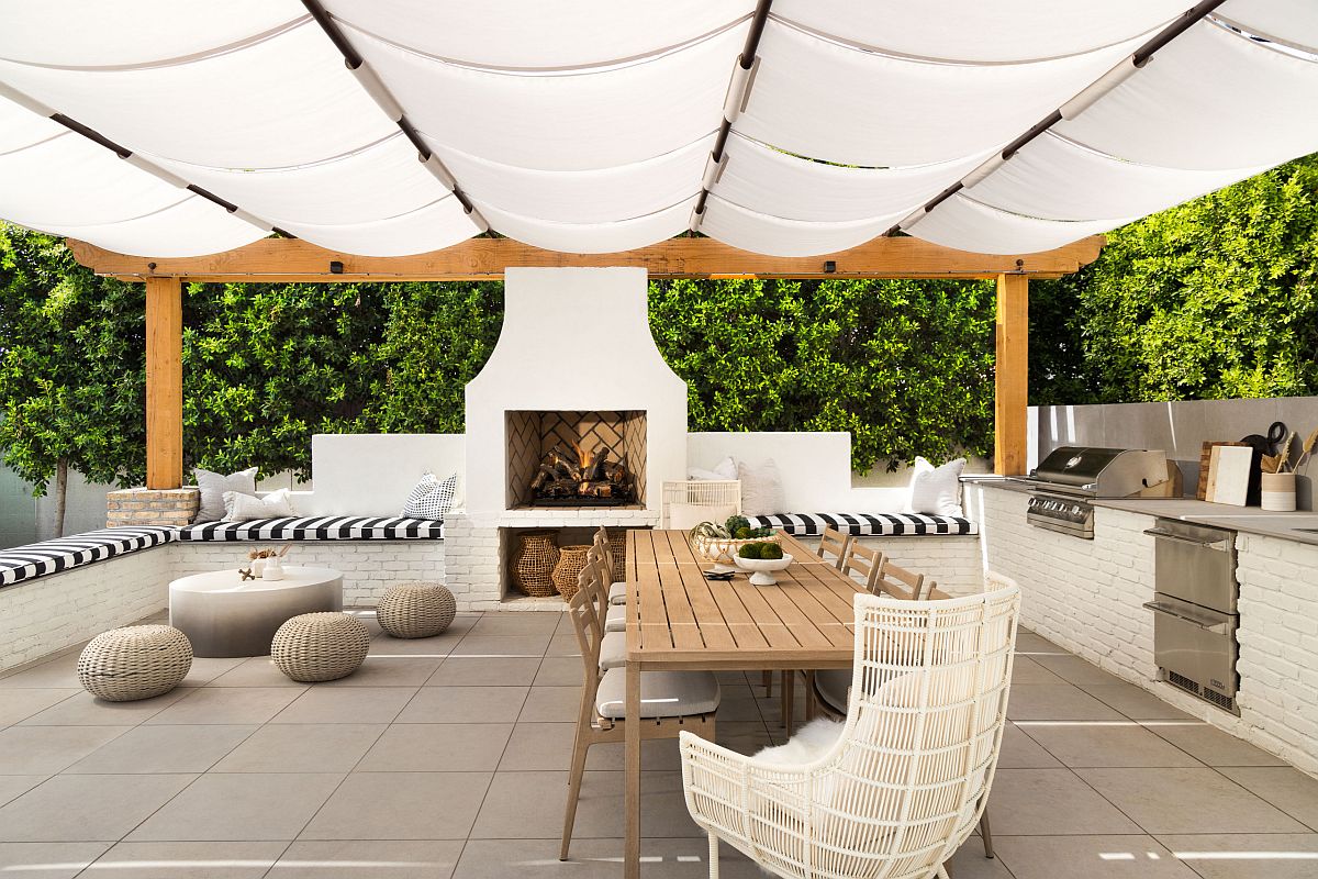 Delightful outdoor living space complete with outdoor kitchen, fireplace and a shade that brings Mediterranean touches to it