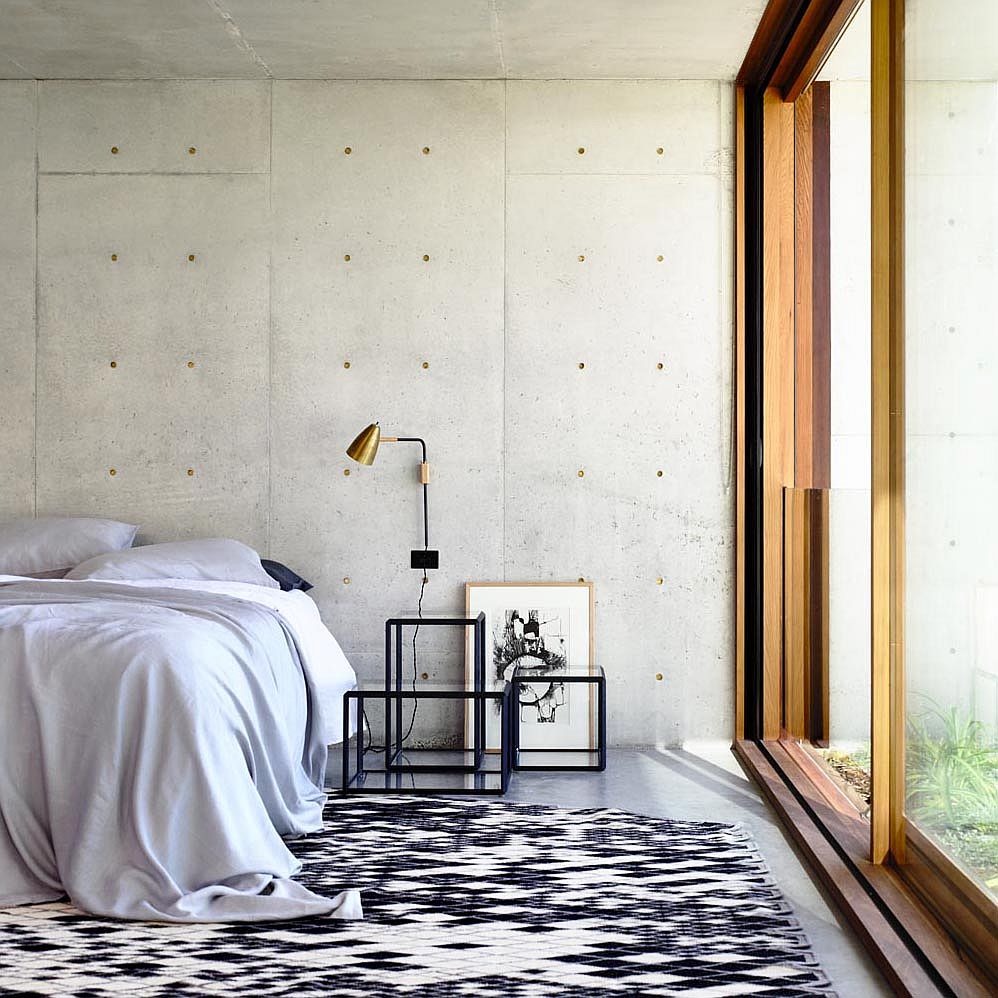 Exposed concrete walls create a modern minimal backdrop in the bedroom with sliding glass doors