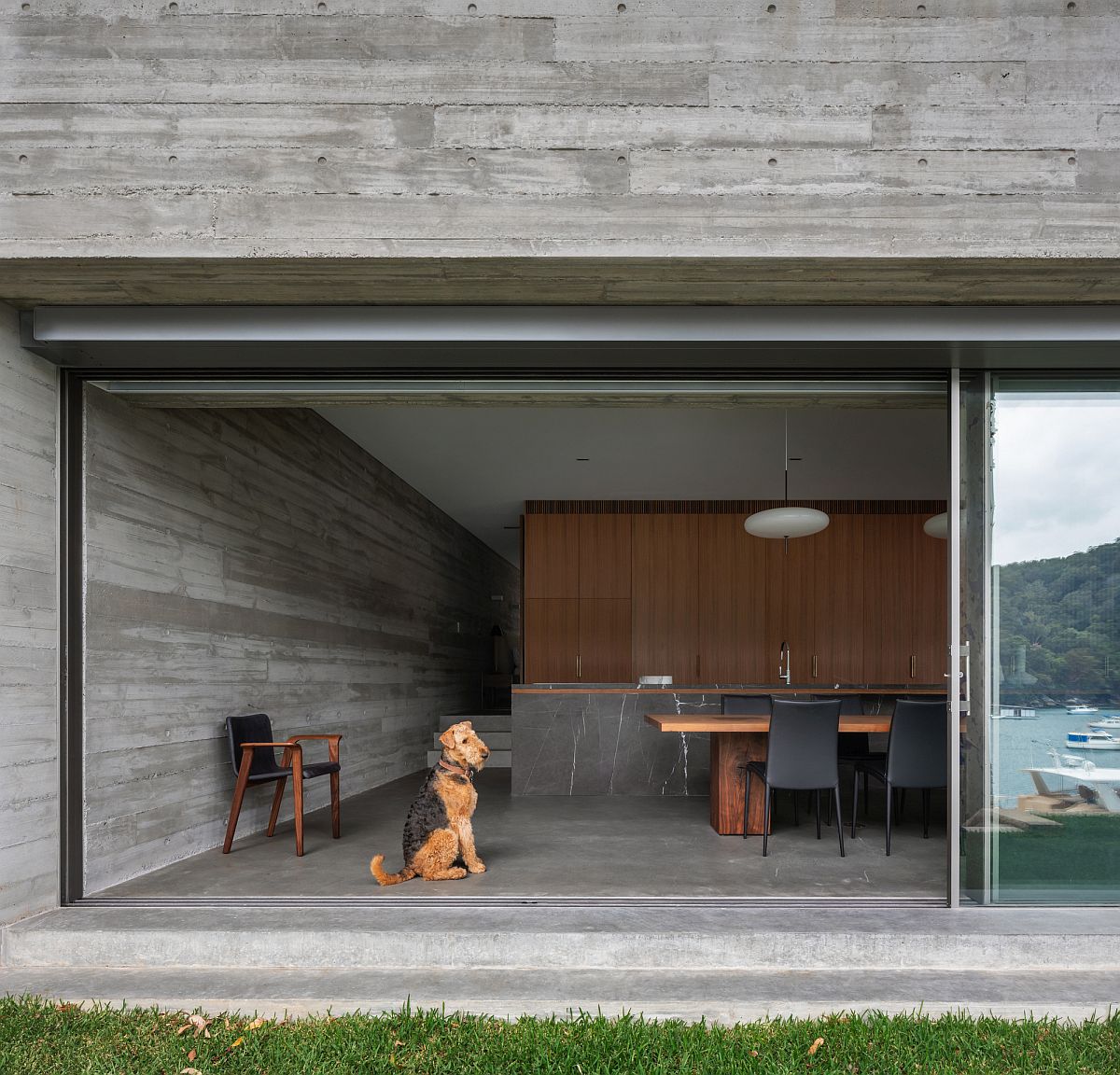 Exposed concrete walls shape the interior of the house with sliding glass walls connecting it to th exterior