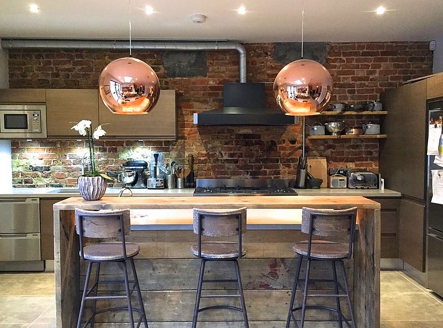 Kitchen island in reclaimed wood along with sparkling copper pendants used in the small industrial kitchen