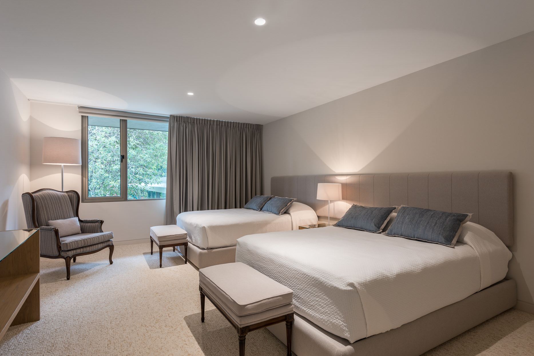 Modern bedroom in gray and white with twin beds and a chair in the corner