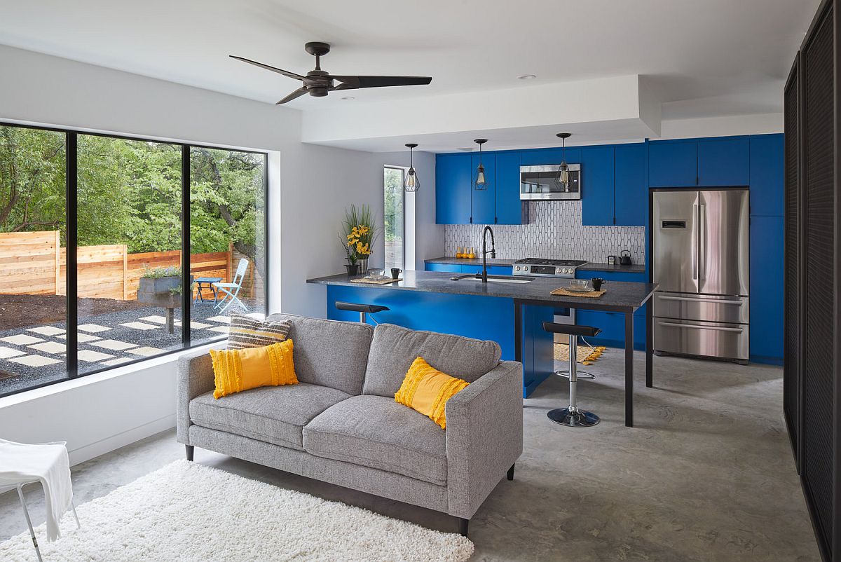 Modern kitchen inside he Texas home with bright blue cabinets and a relaxing sitting area next to it