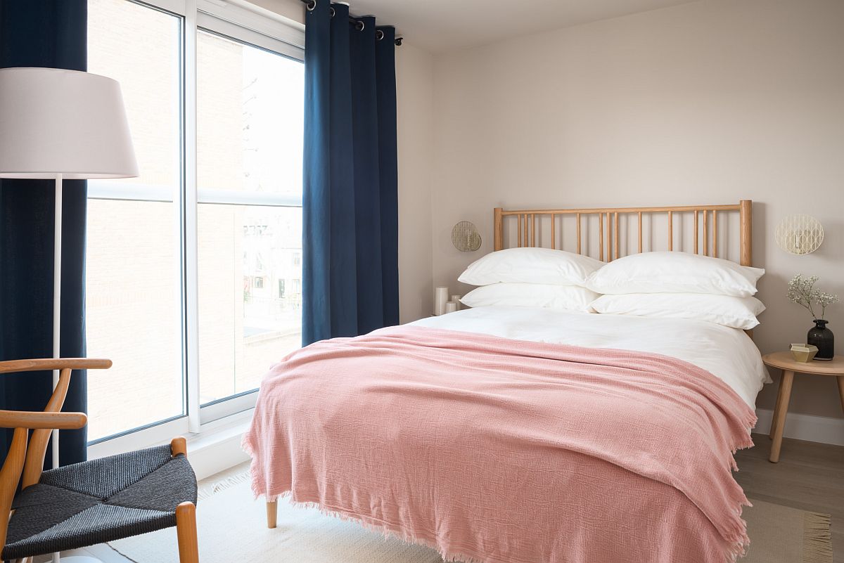 Navy blue drapes and pink bed sheets usher color into this Scandinavian style bedroom